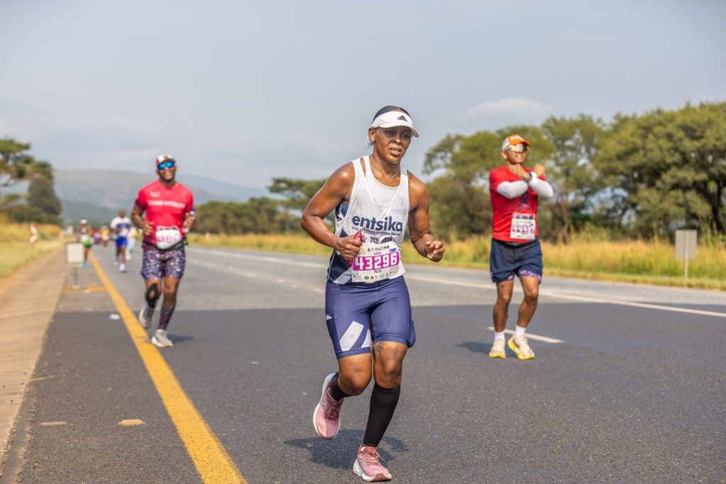 A marathon runner in a white vest pushing up the N4